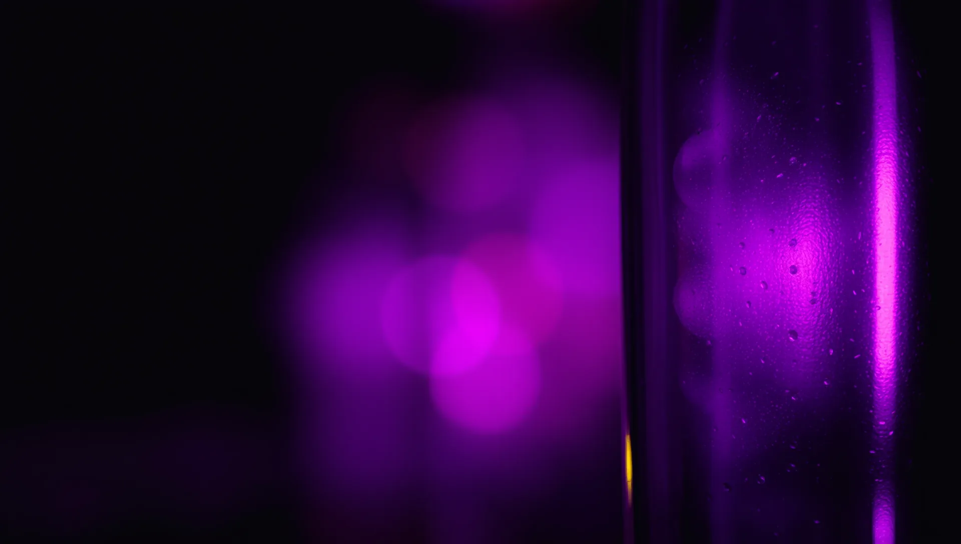 Soft bokeh of violet and amber lights through frosted glass, dark and moody